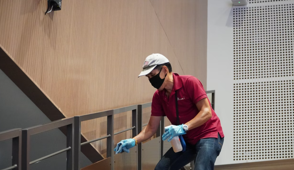 Person disinfecting the surface of a commercial building.