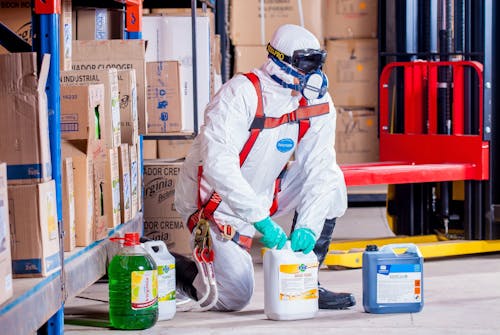 A person in PPE diligently working with cleaning chemicals.